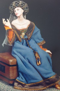 Jean de Froissart, one of the greatest of the troubadours, inspired this figure of a medieval maiden who sits enraptured by his poetry. All details of costuming—from roundlet (padded green velvet headdress) to reliquary were meticulously re-created by Maggie. Amiette de Froissart